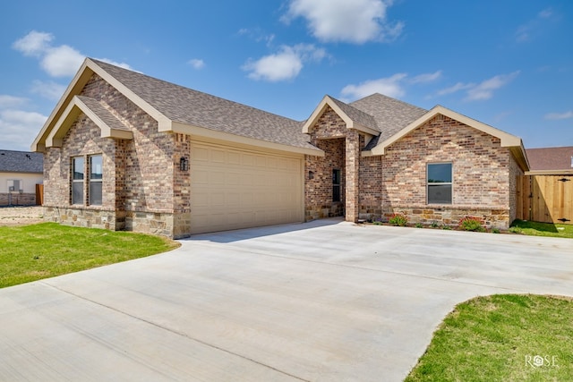 5441 Riviera Ln, San Angelo, TX 76904 - ranch-style house featuring stone siding, brick siding, concrete driveway, roof with shingles, and an attached garage