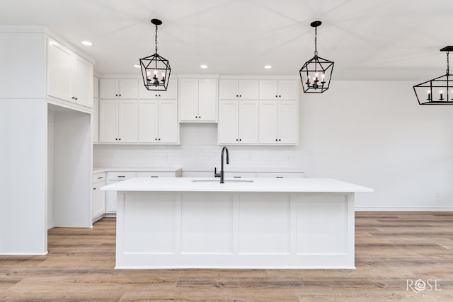 kitchen featuring light countertops, hanging light fixtures, a sink, and a center island with sink