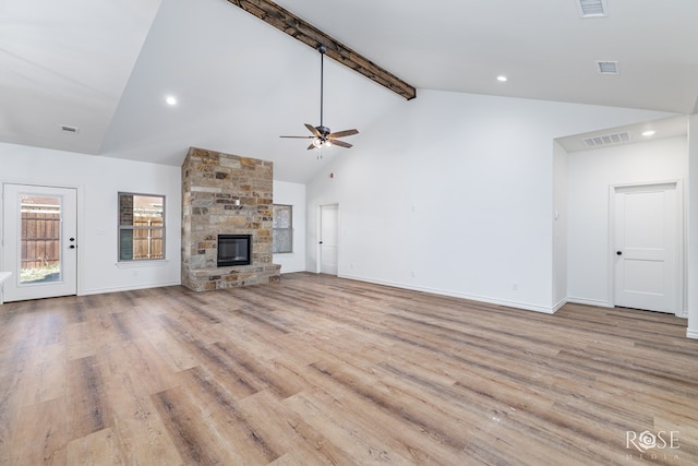 unfurnished living room with beam ceiling, visible vents, a fireplace, and light wood finished floors