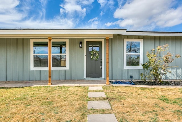 view of exterior entry featuring board and batten siding and a lawn