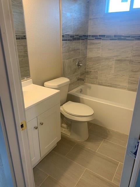 full bathroom with vanity, tiled shower / bath, tile patterned floors, and toilet