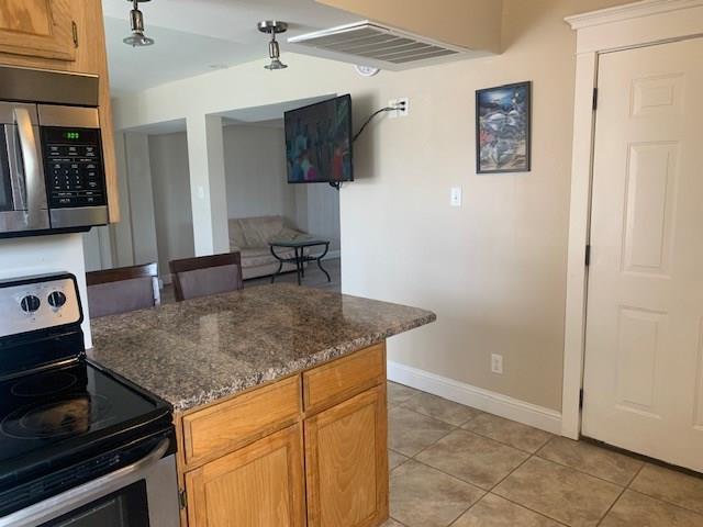 kitchen with light tile patterned floors, dark stone counters, and appliances with stainless steel finishes