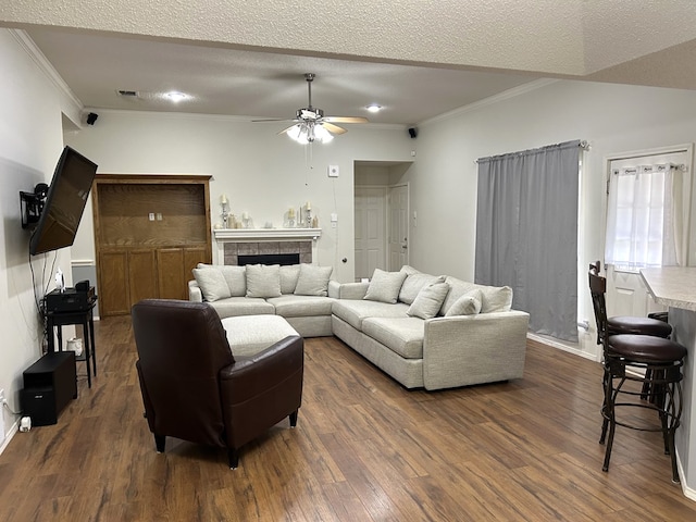 3570 Grandview Dr, San Angelo, TX 76904 - living room with ceiling fan, dark wood finished floors, crown molding, a tiled fireplace, and a textured ceiling