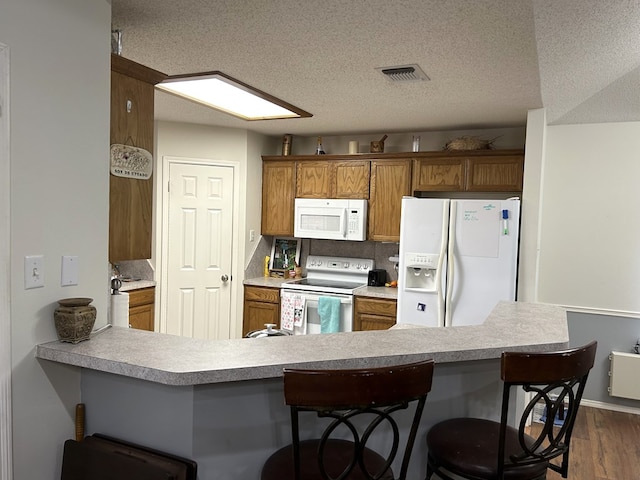 3570 Grandview Dr, San Angelo, TX 76904 - kitchen with white appliances, a textured ceiling, dark wood-style floors, brown cabinets, and light countertops