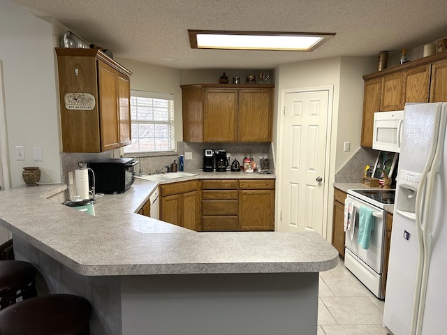 3570 Grandview Dr, San Angelo, TX 76904 - kitchen with white appliances, light countertops, a peninsula, brown cabinetry, and a textured ceiling