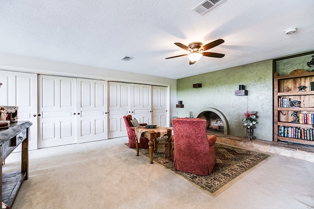 6290 Stokes Rd, San Angelo, TX 76904 - carpeted living room with a fireplace with raised hearth, a ceiling fan, and a textured ceiling