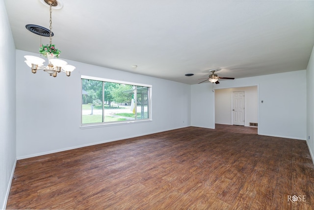 empty room with ceiling fan with notable chandelier and dark wood-type flooring