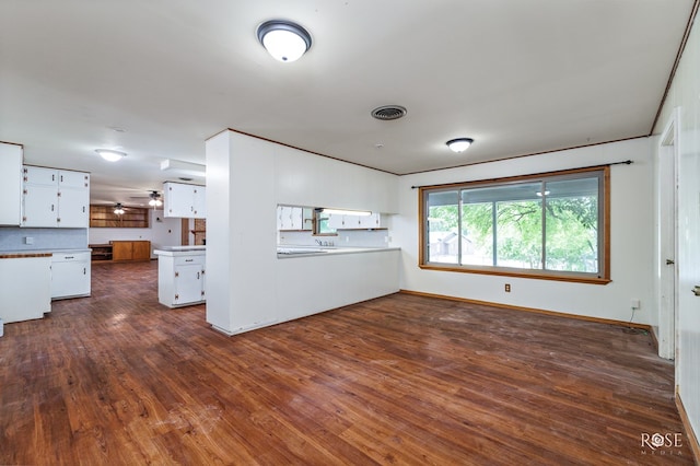 unfurnished living room featuring dark wood-type flooring and ceiling fan