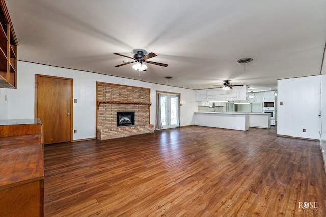 unfurnished living room with hardwood / wood-style flooring, ceiling fan, a brick fireplace, and french doors