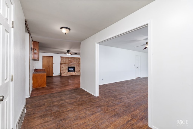 unfurnished living room featuring ceiling fan, dark hardwood / wood-style floors, and a fireplace