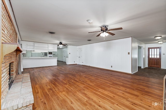 unfurnished living room with hardwood / wood-style flooring, ceiling fan, and a fireplace