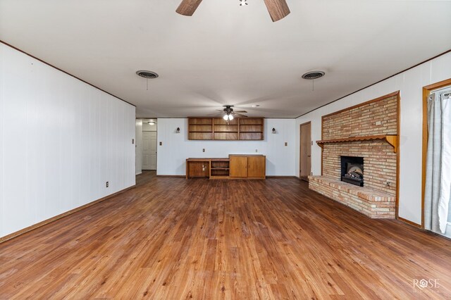 unfurnished living room with ceiling fan, hardwood / wood-style floors, and a brick fireplace