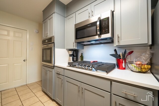 kitchen featuring light tile patterned floors, gray cabinets, and appliances with stainless steel finishes