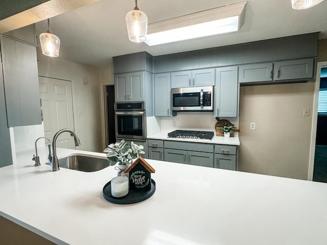 kitchen with pendant lighting, sink, stainless steel appliances, and kitchen peninsula