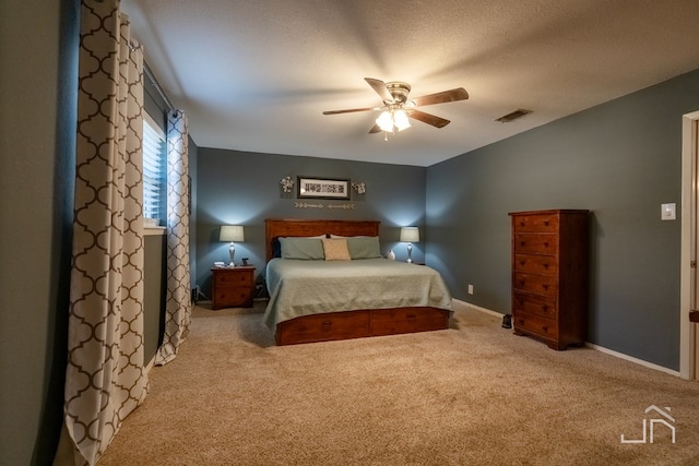 bedroom with ceiling fan, light carpet, and a textured ceiling