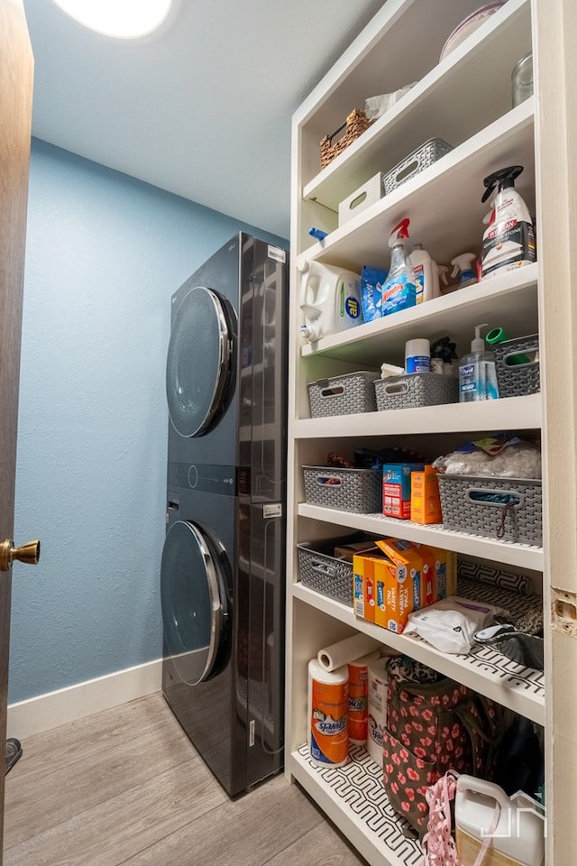 clothes washing area featuring light hardwood / wood-style flooring and stacked washer / dryer