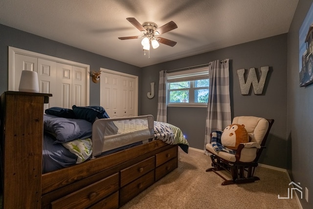 bedroom featuring light carpet, multiple closets, and ceiling fan