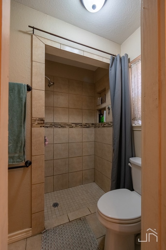 bathroom with a shower with shower curtain, tile patterned floors, and toilet