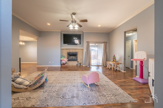 living area with ornamental molding, a fireplace, baseboards, and wood finished floors