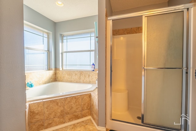 bathroom featuring a bath, a shower stall, tile patterned floors, and a textured ceiling