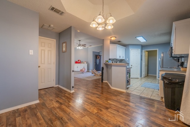 kitchen featuring wood finished floors, visible vents, baseboards, white cabinets, and ceiling fan with notable chandelier