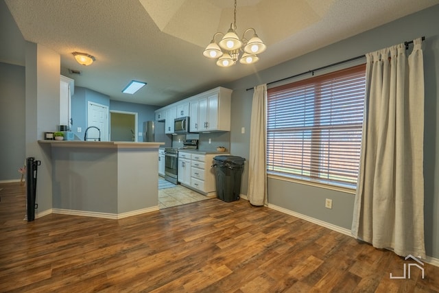 kitchen featuring appliances with stainless steel finishes, white cabinetry, a peninsula, and wood finished floors