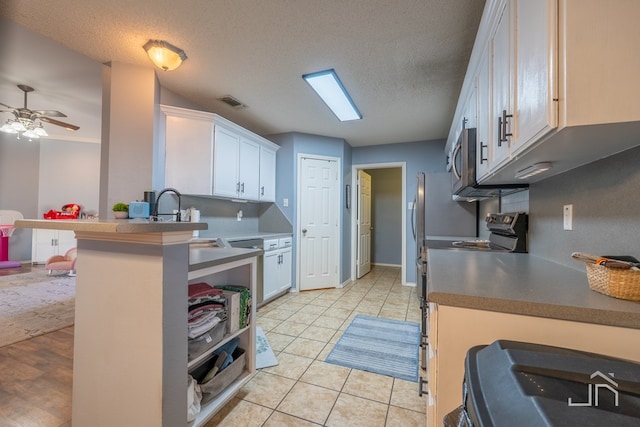 kitchen featuring visible vents, a sink, white cabinetry, light tile patterned floors, and range