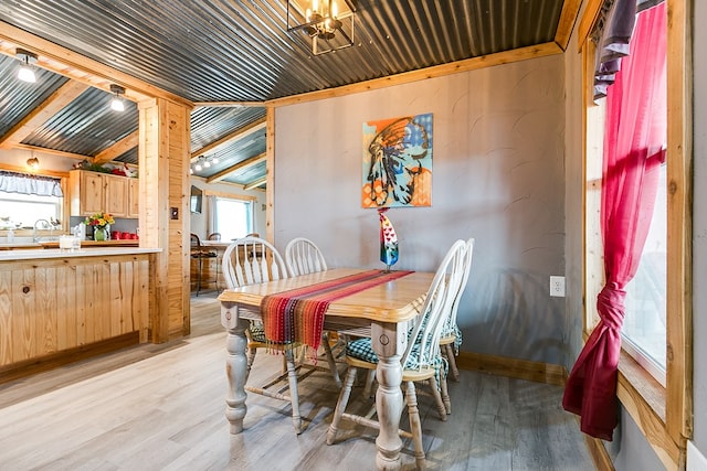 dining room with vaulted ceiling, sink, a notable chandelier, and light wood-type flooring