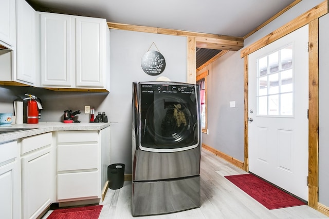 clothes washing area featuring cabinets, sink, and light hardwood / wood-style flooring