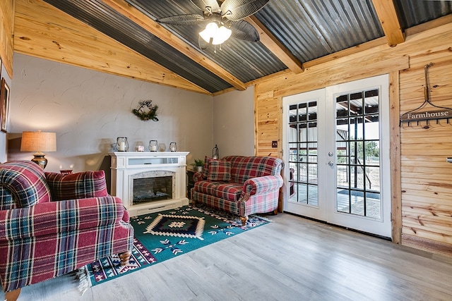 living room with wood walls, lofted ceiling with beams, wood-type flooring, a high end fireplace, and french doors