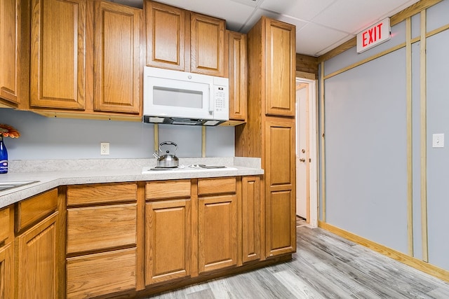 kitchen with white appliances, a paneled ceiling, and light wood-type flooring