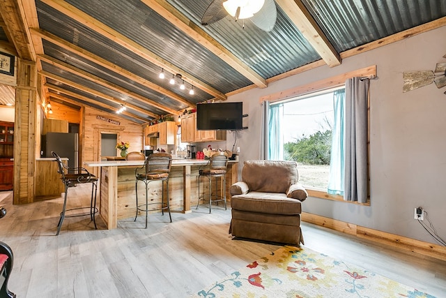 interior space featuring light hardwood / wood-style flooring, stainless steel fridge, lofted ceiling with beams, and ceiling fan