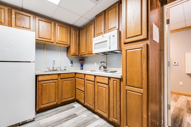 kitchen with white appliances, a paneled ceiling, sink, and light hardwood / wood-style flooring