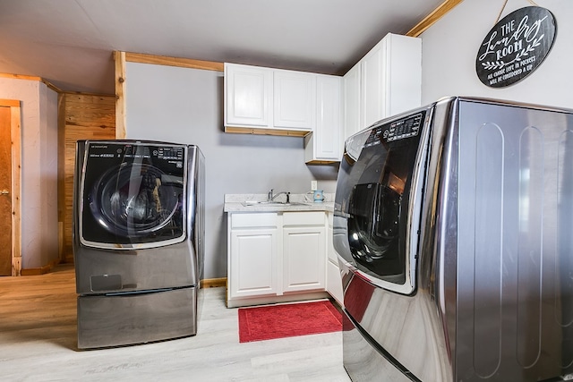 washroom with separate washer and dryer, sink, light hardwood / wood-style floors, and cabinets