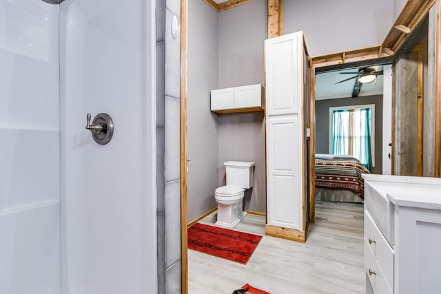 bathroom with ceiling fan, wood-type flooring, a shower, and toilet