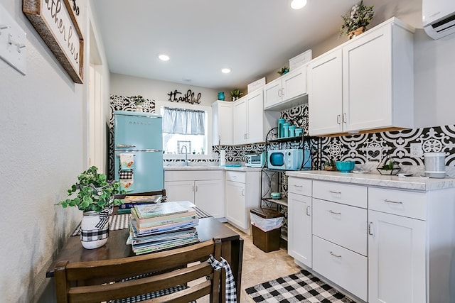 kitchen featuring sink, white cabinetry, an AC wall unit, fridge, and backsplash