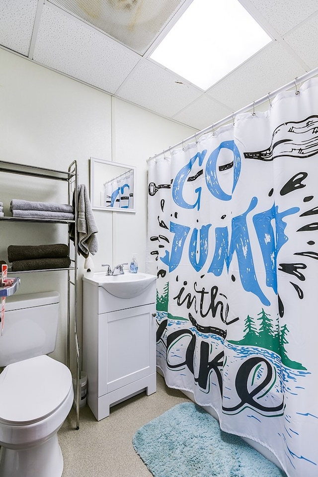 bathroom featuring vanity, toilet, and a drop ceiling