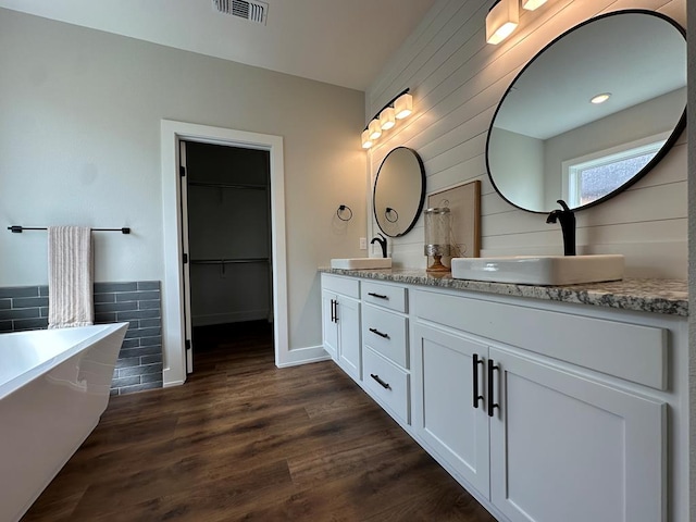 3611 Clearview Dr, San Angelo, TX 76904 - bathroom with double vanity, a freestanding bath, wood finished floors, and a spacious closet