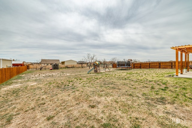 view of yard with a shed, a fenced backyard, an outdoor structure, a playground, and a trampoline