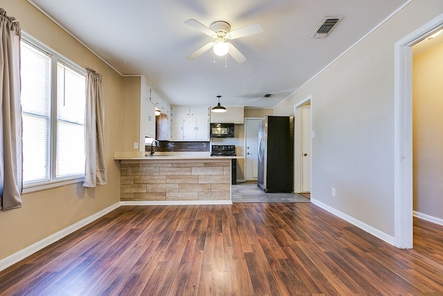 kitchen with kitchen peninsula, sink, white cabinets, black appliances, and dark wood-type flooring