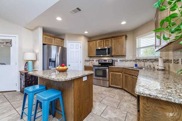 kitchen featuring sink, a breakfast bar area, decorative backsplash, a center island, and stainless steel appliances