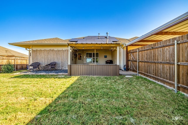 rear view of house with a lawn and solar panels