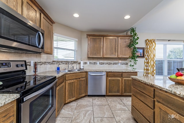 kitchen with light stone counters, sink, tasteful backsplash, and appliances with stainless steel finishes