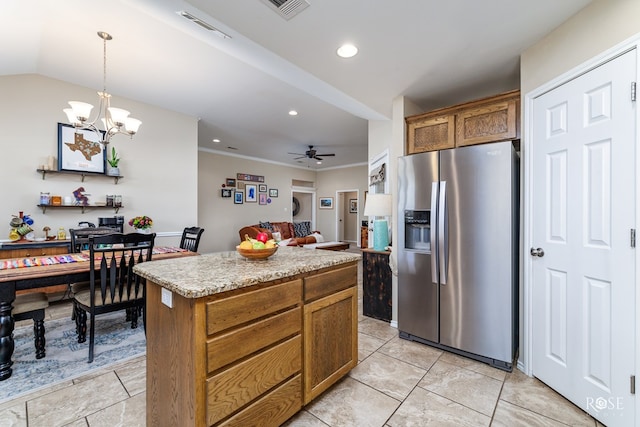 kitchen with light stone counters, decorative light fixtures, a center island, stainless steel fridge, and ceiling fan with notable chandelier