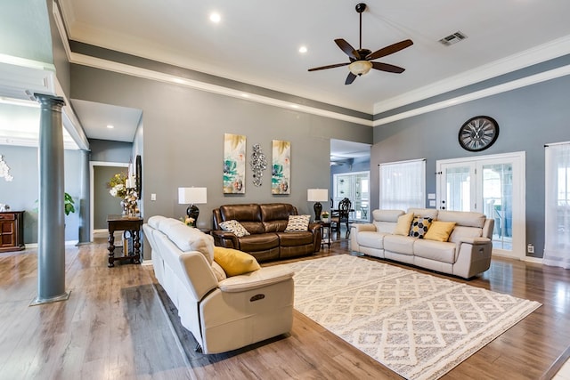 living room featuring crown molding, ceiling fan, wood-type flooring, and decorative columns