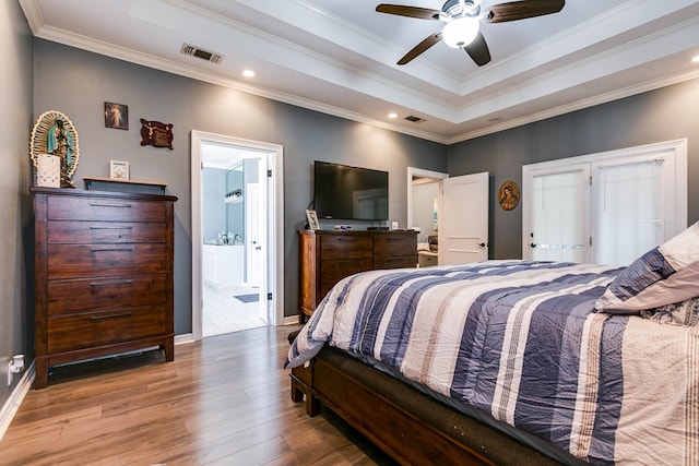 bedroom with crown molding, connected bathroom, hardwood / wood-style flooring, and ceiling fan