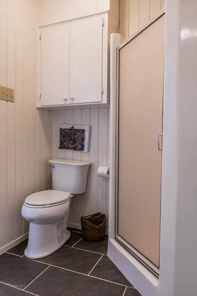 bathroom with tile patterned flooring, an enclosed shower, and toilet