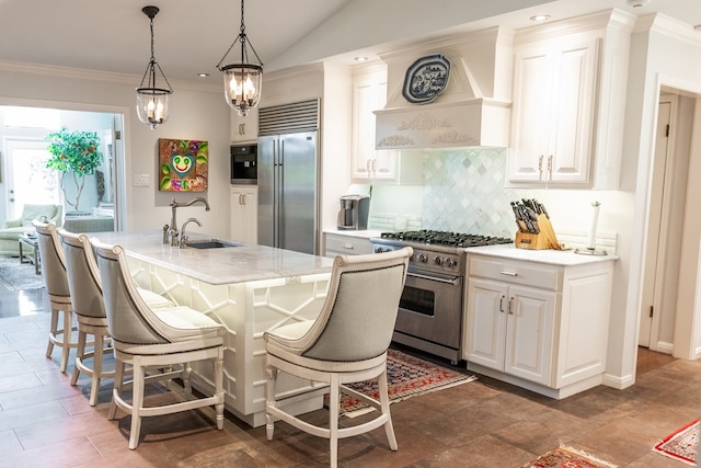 kitchen with sink, white cabinetry, backsplash, premium appliances, and an island with sink