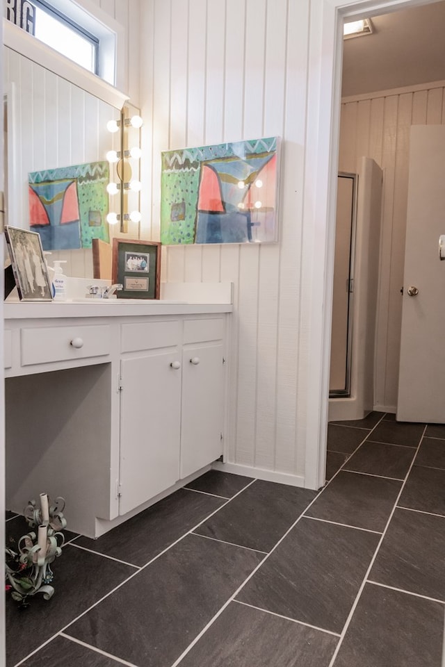 interior space featuring white cabinetry, dark tile patterned flooring, and wood walls