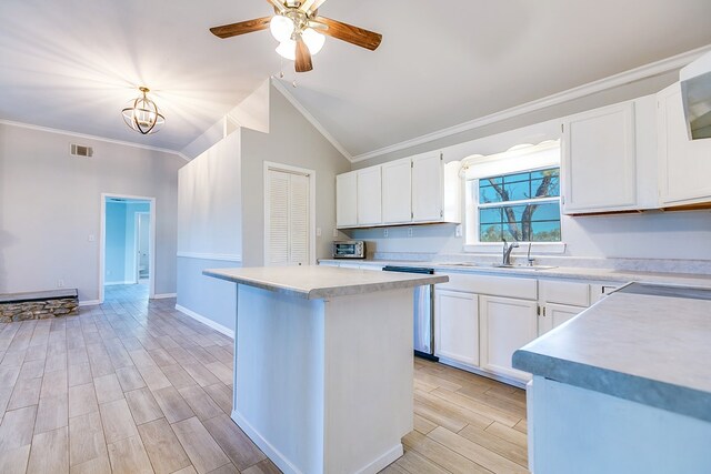 kitchen featuring vaulted ceiling, a kitchen island, sink, white cabinets, and ornamental molding